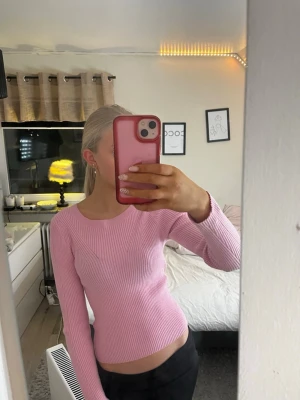 Rosa ribbstickad tröja med rund hals - Säljer en ljusrosa, ribbstickad tröja med rund halsringning och långa ärmar. Tröjan är figurnära och har en enkel, stilren design utan synliga loggor eller detaljer. Perfekt för dig som gillar en clean och feminin look.