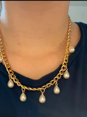 Guldhalsband med droppformade pärlor - Snyggt halsband i guldfärgad metall med grov kedja och droppformade vita pärlor som hänger längs hela halsbandet. Justerbar längd med karbinlås. Perfekt för dig som vill ha ett statement-smycke med trendig känsla. Handgjort!!!!