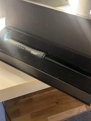 Svart locktång från LYKO - Snygg svart locktång från LYKO med digital display och smal konisk form. Handtaget har tydliga knappar och en blå detalj vid sladden. Perfekt för att skapa mjuka lockar eller vågor i håret. Kommer i en stilren svart förpackning.