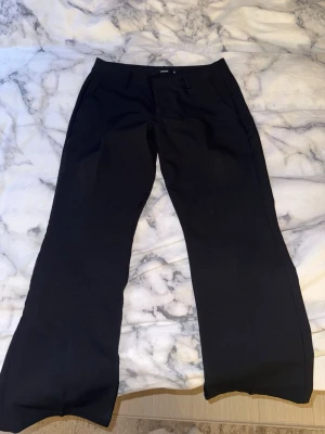 Svarta kostymbyxor med raka ben - Säljer ett par svarta kostymbyxor med raka ben och pressveck från Bikbok. Byxorna har fickor fram och hällor för skärp i midjan. Perfekta för en clean och stilren look. Materialet känns mjukt och har en lätt stretch för extra komfort. Dem är bekväma och sitter mycket fint på kroppen. Jag har haft på mig dem några gånger men finns inga defekter.  Kan skicka fler bilder privat!