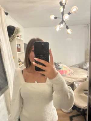 Vit stickad tröja med fyrkantig ringning - Mysig vit stickad tröja med lång ärm och trendig fyrkantig ringning. Passar dig som gillar en enkel men stilren look.