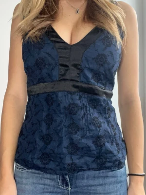 Mörkblå blommig linnetopp med satin - Snygg mörkblå linnetopp med blommigt mönster och svarta satindetaljer. Den har inga defekter och är i storlek M