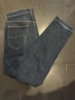 Mörkblå DAREN ZIP FLY jeans med kontrastsömmar - Snygga mörkblå DAREN ZIP FLY jeans med klassiska kontrastsömmar och femficksdesign. Jeansen har en smal passform och är tillverkade i ett stretchigt denimtyg som sitter bekvämt. Perfekta för en trendig och avslappnad look.