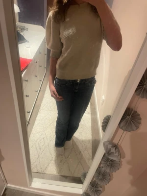 Stickad tröja från Vero Moda  - Snygg beige stickad tröja med puffärmar och rund halsringning. Tröjan har korta ärmar och en rak, avslappnad passform. Materialet är mjukt och bekvämt. Lite noppig men fortfarande bra skick 