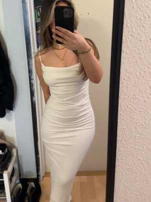 Vit långklänning med smala axelband - Säljer en elegant vit långklänning med smala axelband och figurnära passform. Klänningen har en enkel och stilren design som framhäver siluetten. Perfekt för dig som gillar minimalistisk stil och vill ha en klänning som känns både trendig och tidlös. Passar perfekt inför studenten och sommaren. 
