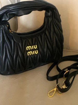 Svart quiltad handväska från Miu Miu - Svart handväska från Miu Miu i quiltat läder. Kommer med axelrem till. Den är helt oanvänd.