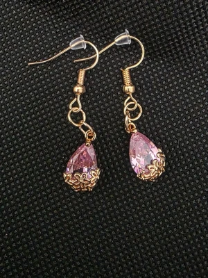 Rosa droppformade örhängen i guld - Snygga örhängen med droppformade rosa stenar och guldfärgade detaljer. Stenarna är infattade i små blommiga dekorationer som ger en romantisk och trendig känsla. Perfekta för att lyfta din stil med lite extra färg och glans.