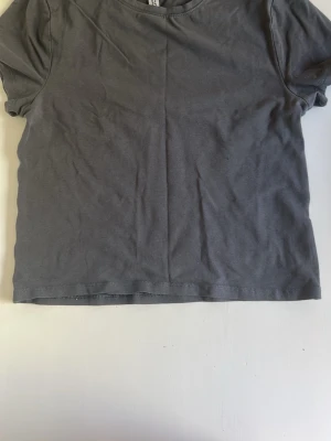 Mörkgrå basic t-shirt - En enkel mörkgrå t-shirt i mjuk bomull. Klassisk rund halsringning och korta ärmar. Perfekt till jeans eller shorts för en avslappnad look.