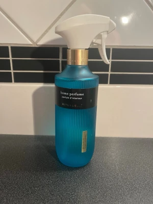 Blå Rituals home perfume spray - Säljer en blå home perfume spray från Rituals, The Ritual of Karma. Flaskan är gjord av blått frostat glas med gulddetaljer och har en vit spraypump. Perfekt för att fräscha upp hemmet med en lyxig doft. Kolla mängd på bild. 