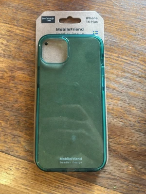 Genomskinligt mobilskal i grönt - Snyggt grönt genomskinligt mobilskal från MobileFriend i mörkgrön färg, designat för iPhone 14 Plus. Skalets material är tåligt och greppvänligt, stötdämpande och stödjer trådlös laddning. Svensk design och veganskt material. Säljer för jag köpte fel, jag har 14 pro plus  