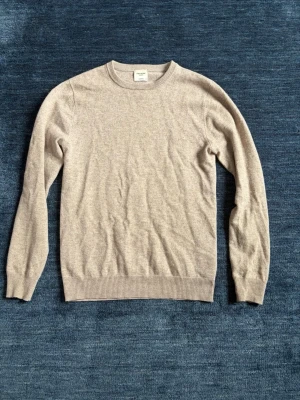 John Henric Kashmirtröja - Klassisk beige stickad tröja. Tillverkad i kashmir. Perfekt basplagg för lager på lager och enkel att matcha med olika stilar. Storlek XS passar XS o S. Nypris 2500kr.