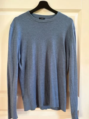 Blå stickad tröja från Massimo Dutti - Snygg blå stickad tröja från Massimo Dutti i mjukt material. Tröjan har rund halsringning och långa ärmar, perfekt för lager på lager. Enkel och stilren design som passar till det mesta.