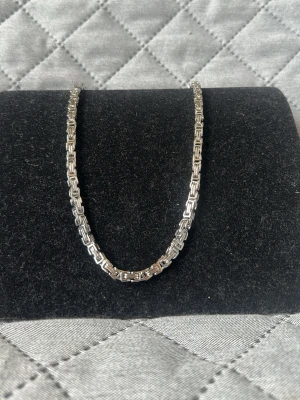 Silverfärgat kedjehalsband - Snyggt halsband i silverfärg med en robust och fyrkantig kedjedesign. Halsbandet har en blank finish och ett klassiskt karbinlås. Perfekt för dig som gillar stilrena accessoarer med lite edge. Materialet är i rostfritt stål. 50 cm. Checka in min profil för passande armband.