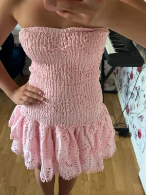 Rosa bandeauklänning från DESIGN BY AMOR  - Supersöt rosa bandeauklänning från DESIGN BY AMOR med smockad överdel och volangig kjol. Superskönt och stretchigt material!🌸Helt ny med lappen kvar! Skicka gärna prisförslag och hör av dig om du har frågor❣️