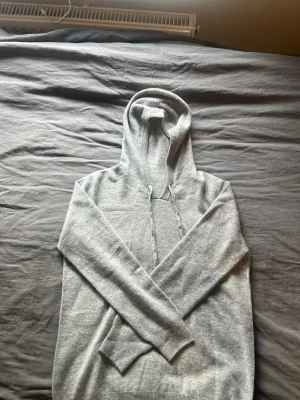 Kashmir hoodie  - Säljer en stilren ljusgrå hoodie med huva. Är storlek S men passar även XS. Säljer då jag fick den i present av min Farfar från Skottland men den ej passar. 