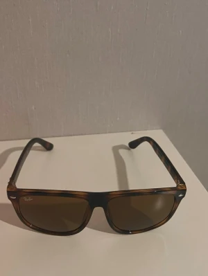 Bruna Ray-Ban solglasögon boyfriend - Snygga solglasögon från Ray-Ban i klassisk wayfarer-modell. Bågarna är bruna med sköldpaddsmönster och glasen är mörka. Perfekta för soliga dagar och ger en cool vibe till din outfit. Helt nya! Köpt på marknad utomlands