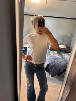 Vit basic t-shirt i bomull - Säljer ett par blå bootcut jeans med slitningar på låren och knäna från Gina 14+. Stoerlel M men passar mig som vanligtvis använder S🥰