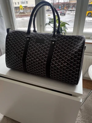 Brun weekendbag från Go4yard - Snygg brun weekendbag från Go4yard med det klassiska vita mönstret över hela väskan. Väskan har två robusta handtag. Perfekt för resor när du vill ha både stil och funktion.