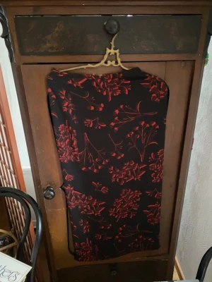 Svart långkjol med rött blommönster - Snygg svart långkjol med röda blommor i ett elegant mönster. Kjolen har en rak och klassisk form som passar perfekt till många olika stilar. Materialet känns mjukt och följsamt mot kroppen. (möts upp i Stockholm)