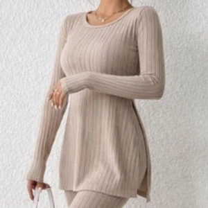 Beige ribbad långärmad tröja - Stilren beige ribbstickad tröja med lång ärm och rund halsringning. Tröjan har en längre, rak passform och slits i sidorna för extra rörelsefrihet. Perfekt att matcha med jeans eller leggings för en avslappnad look.