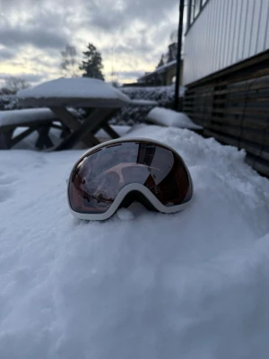 Vita skidglasögon med spegelglas - Säljer ett par snygga skidglasögon från cross sportswear med vitt band och ram. Glaset är spegeltonat i en mörk nyans som ger cool look och skyddar mot starkt ljus. Perfekta för dig som vill sticka ut i backen och ha bra sikt i snön.