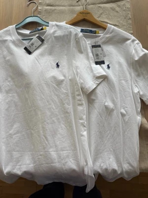 Vit t-shirt från Polo Ralph Lauren - Klassisk vit t-shirt från Polo Ralph Lauren med broderad logga på bröstet. T-shirten har rund hals, korta ärmar och är tillverkad i mjuk bomull. Perfekt basplagg med stilren design och skön passform. 