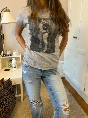 Grå t-shirt med Håkan Hellström-tryck - Säljer en grå t-shirt med coolt svartvitt tryck av Håkan Hellström och texten 'Det kommer aldrig va över för mig'. T-shirten har korta ärmar och är gjord i mjuk bomull. Perfekt för dig som gillar svensk musik och vill ha en unik t-shirt.