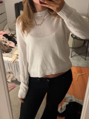 Vit croppad stickad tröja - Säljer en vit croppad stickad tröja med rund hals och långa ärmar. Tröjan har ribbade muddar vid ärmslut och nederkant, vilket ger en snygg och avslappnad look. Perfekt att matcha med höga jeans eller kjol.