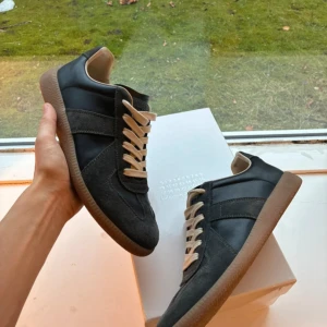 Svarta sneakers Maison Margiela - Säljer ett par Maison margiella gats i storlek 38/39 färgen är svart/grå. 100% äkta kommer med box och alla tillbehör.  Skorna helt nya/ använts 3-4 gngr