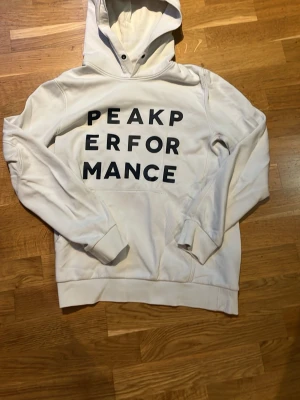 Vit hoodie från Peak Performance - Snygg vit hoodie från Peak Performance med blå text på bröstet🔥 Storlek Small📏 Fraktar inom 1-2 dagar💨📦 Hör av er vid funderingar!😊