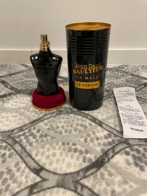 Helt ny Jean Paul Gaultier Le Male Le Parfum - Jean Paul Gaultier Le Male Le Parfum i en svart, kroppformad flaska med gulddetaljer. Kommer med en svart och guld cylinderformad förpackning och står på en röd sammetsliknande bas. En ikonisk och lyxig herrdoft.