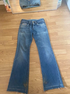 Blå bootcut jeans med råa kanter - Säljer dessa jättesnygga vintage bootcut lowwaist diesel jeans då de tyvärr är för små för mig. Storlek 26 (ungefär XS/S). Liten Fläck på nedre delen av första bilden men skall tvätta jeansen innan jag skickar!