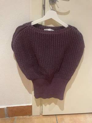 Mörklila stickad tröja från Zara - Säljer en chunky mörklila stickad tröja från Zara med bred ribbad midja och ballongärmar. Tröjan har grovstickad struktur och rund halsringning. Perfekt för dig som gillar oversized och trendig look.