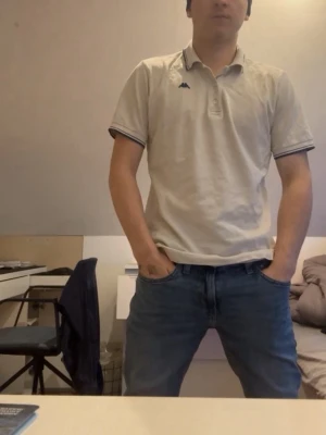 Beige pikétröja från Kappa - Säljer en beige pikétröja från Kappa med klassisk krage och knappar framtill. Tröjan har mörka detaljer på ärmslut och krage samt Kappa-loggan på bröstet. Perfekt för dig som gillar en enkel och stilren look.