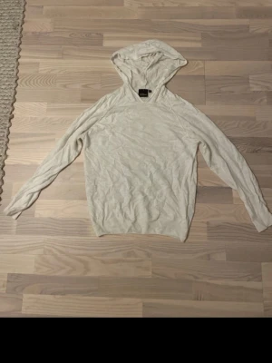 Vit hoodie från Oscar Jacobson - Säljer en tunn, vit hoodie från Oscar Jacobson.  Stickad avslappnad passform med huva. Materialet känns lätt och luftigt, perfekt för lager på lager eller chill dagar. Klassisk design utan tryck eller detaljer. Liten fläck som går att få bort