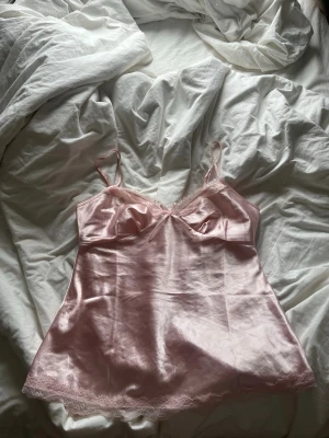 Rosa satin nattlinne med spetsdetaljer - Snyggt ljusrosa nattlinne i satin med tunna axelband och spets detaljer från Missäy i storlek M. Ett hål på vänster sidan som man ser på bild 3 men som enkelt går att sy💞