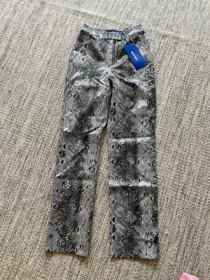 Nya Ormmönstrade jeans från Karl Lagerfeld - Snygga raka jeans med grått och svart ormmönster från Karl Lagerfeld. Hög midja och klassisk femficksmodell med dragkedja och knapp framtill. Perfekta för dig som vill sticka ut med en cool look.