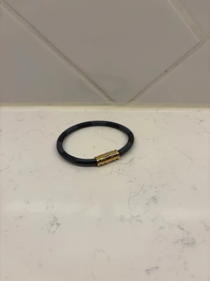 Svart läderarmband med guldlås - Stilrent svart armband i flätat läder med ett snyggt magnetlås i guldfärgad metall. Perfekt accessoar för dig som gillar en enkel men cool look. Passar både till jeans och skjorta. Armbandet är 19 cm långt. Hör av er gällande funderingar!!