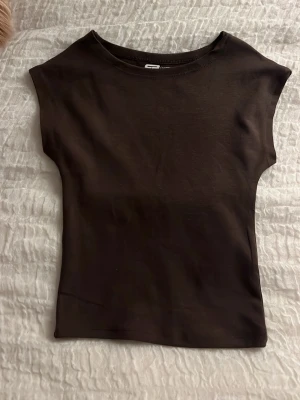 Brun topp - En enkel brun topp. Modellen är ärmlös och tight passform. Ej använd.