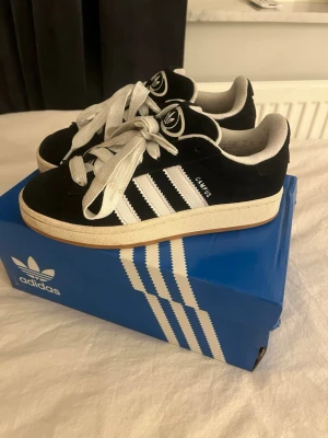 Adidas Campus svarta sneakers - Klassiska Adidas Campus sneakers i svart mocka med vita detaljer. Använda 3 gånger. Du får även med original lådan till skorna💕då jag tog bilden när det va mörkt ute så ser dom mörkare ut på bilden kan så klart lösa bättre bilder! Pris går o diskutera 