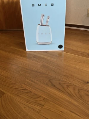Smeg knivblock med knivar, Svart - Snyggt knivblock från Smeg i Svart med matchande knivar i rostfritt stål. Blocket har en rundad form och tydlig Smeg-logga framtill. Perfekt för att hålla köksknivarna organiserade och nära till hands.