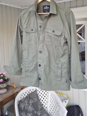 Olivgrön overshirt från Hollister - Stilren olivgrön overshirt från Hollister med klassisk krage, knäppning framtill och två bröstfickor med lock. Tillverkad i bomullstyg och har långa ärmar. Inte använda en ända gång i 10/10 skick säljer den pga att den var för stor för mig! Mvh Vilgot 