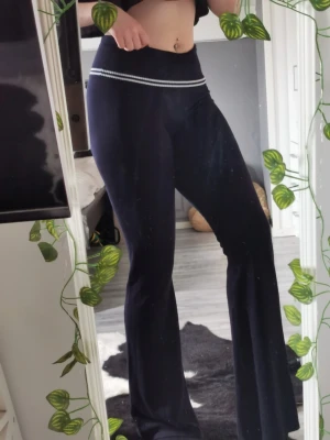 Utsvängda mjukisbyxor - Snygga mjukisbyxor med utsvängda ben och hög midja. Byxorna har en vit randdetalj i midjan som ger en sportig touch. Perfekta för en chill och avslappnad stil.