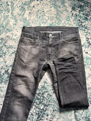 Grå jeans från Levi's - Snygga grå jeans från Levi's med klassisk femficksdesign och raka ben. Jeansen har en lätt tvättad look och detaljer som metallknappar och Levi's ikoniska röda etikett på bakfickan. Perfekta för en avslappnad och trendig stil. Nypris: 1200kr