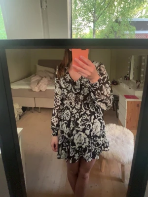 Zara klänning - Supersöt kortklänning med svart botten och stora vita blommor. Klänningen har v-ringning, långa ärmar och ett lätt, fladdrigt tyg som ger en luftig känsla. Pris kan diskuteras vid snabb affär 