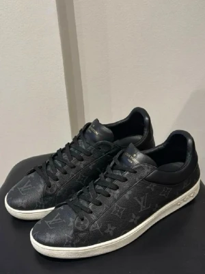 Louis Vuitton sneakers - Louis Vuitton luxenburg skor. Storlek 43 (9). Väldigt fint skick förutom att det har fått lite ”creasing” skada inget som syns vid användning. Se bilder. Dustbags ingår tyvärr ingen box kvar. 