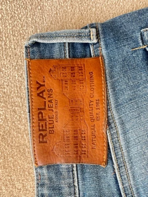 Blå jeans från Replay - Klassiska blå jeans från Replay med raka ben och snygga slitningar på låren. Perfekta för en avslappnad och stilren look. Kanappt använda. W31 L 32