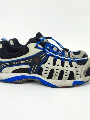 Ecco Receptor sneakers blå Storlek 42 - Snygga Ecco Receptor sneakers i svart mesh med gråa och blå detaljer. Skorna har sportig design, snabbsnörning med blå snören och ventilerande material. Perfekta för dig som gillar en aktiv stil och vill ha bekväma sneakers med cool look.