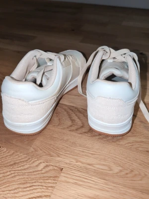 Beige sneakers från Champion - Snygga beige sneakers från Champion med en mix av mocka och textil på ovandelen. Skorna har vita detaljer, klassisk snörning och logga på sidan. Perfekta för dig som gillar en clean och stilren look. St 42 användsa en gång men inte nin färg nypris 700 