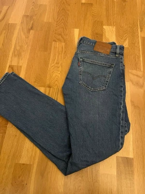 Levi's raka blå jeans - Klassiska blå jeans från Levi’s. Jeansen har en mellanblå tvätt och är tillverkade i slitstark denim med en liten röd etikett på bakfickan. Perfekta för en avslappnad och tidlös stil.